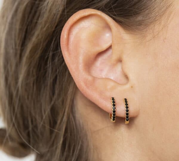 Ces petites créoles sont ornées de pierres de zirconium noir. Elles sont en forme de créole avec une fermeture à loquet. Elles sont plaquées or, ce qui leur donne une finition brillante. Les pierres de zirconium noir sont serties en rangée sur le devant des boucles d’oreilles. Ces pierres sont rondes et facettées, ce qui leur donne un éclat particulier. Ces créoles sont un choix élégant pour toute femme qui apprécie les bijoux raffinés. Le contraste entre l’or brillant et le zirconium noir crée un look à la fois audacieux et sophistiqué. Elles peuvent être portées pour des occasions spéciales ou pour ajouter une touche d’élégance à une tenue de tous les jours. 