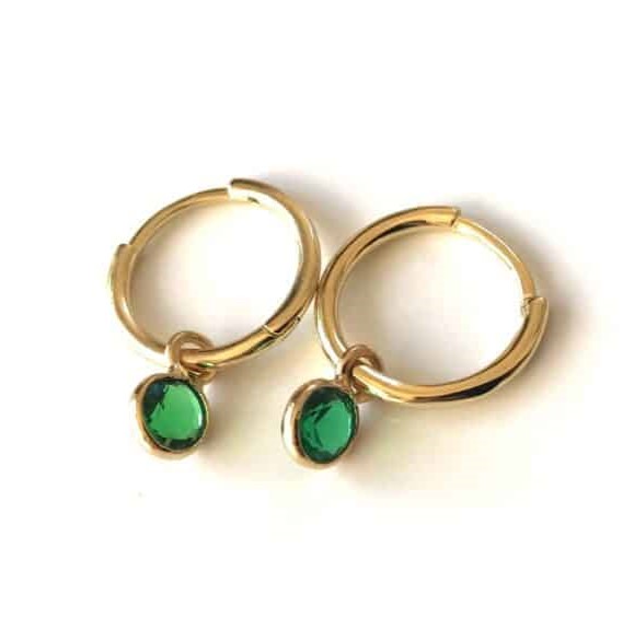 Ces boucles d’oreilles sont des créoles en argent plaqué or de 10 mm avec des petits pendentifs ronds sertis de pierres vert émeraude. Elles sont conçues avec un charme de breloque qui pend légèrement. Les créoles sont fines et le charme est une petite pierre ronde vert émeraude. Elles sont délicates et élégantes, parfaites pour ajouter une touche de couleur à n’importe quelle tenue.