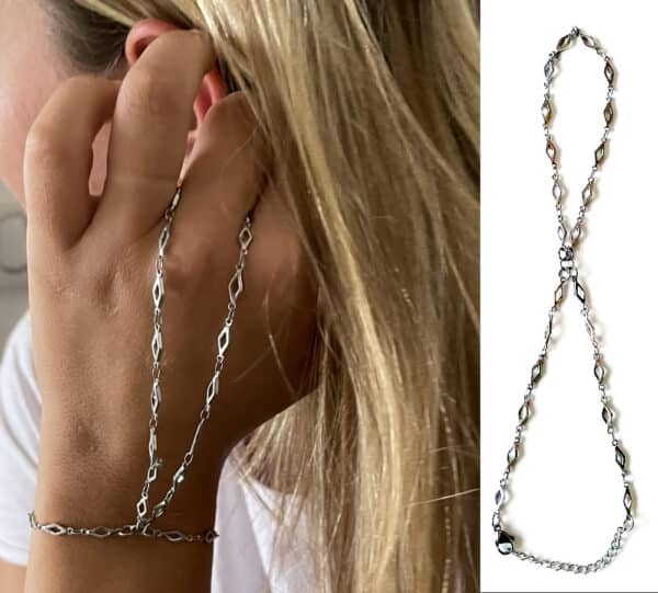 Cette chaine de main est un bijou délicat et élégant qui se compose de maillons interconnectés qui créent un design harmonieux et fluide. Elle est portée autour du pouce, s’étendant sur le dos de la main. Le design est simple mais élégant, avec une brillance métallique distincte. Cette chaine de main est fabriquée en acier inoxydable argenté, ce qui signifie qu’elle est résistante à la rouille, à la corrosion et aux rayures. L’acier inoxydable est également hypoallergénique et ne provoque pas d’allergies ou d’irritations. C’est un matériau durable et facile à entretenir. Elle est terminée par un fermoir mousqueton, sûr et facile d’utilisation et d'une chainette de réglage pour un ajustement parfait au poignet. Ce Bracelet Bague de haute qualité est unique et fabriqué à la main, de façon artisanale dans notre atelier en France.